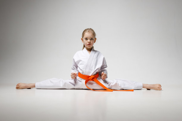 小女孩在白色背景上摆劈叉式，空手道童星。图片下载