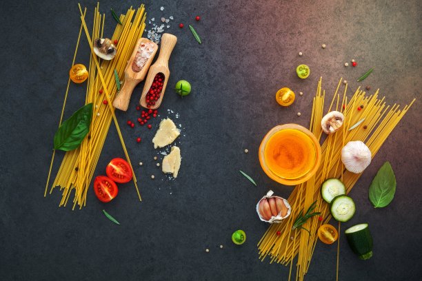 意大利菜的概念。用甜罗勒、番茄、蒜椒、香槟酒、西葫芦和帕玛森奶酪制成的意大利面，在深色背景上平铺并复制空间。图片下载