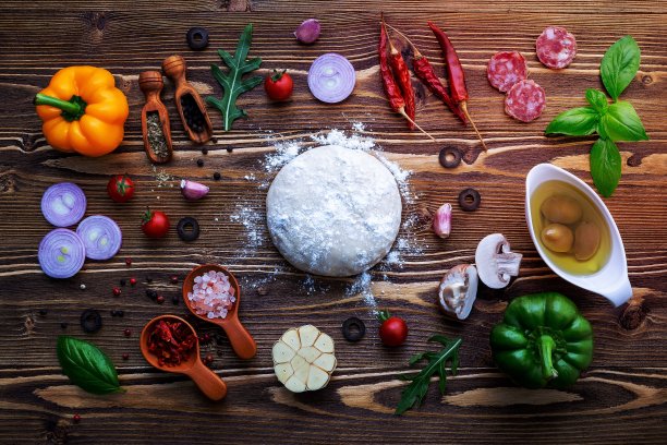 在破旧的木制背景上，生面团和自制披萨的材料。图片下载