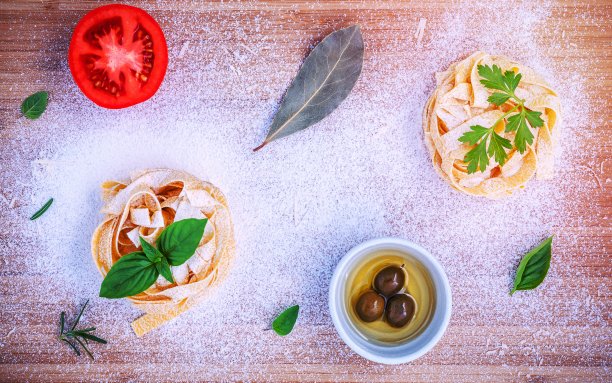 意大利菜的概念。用橄榄油、欧芹、月桂叶、番茄、罗勒等原料制成的意大利宽面条，放在竹砧板上平铺。图片下载