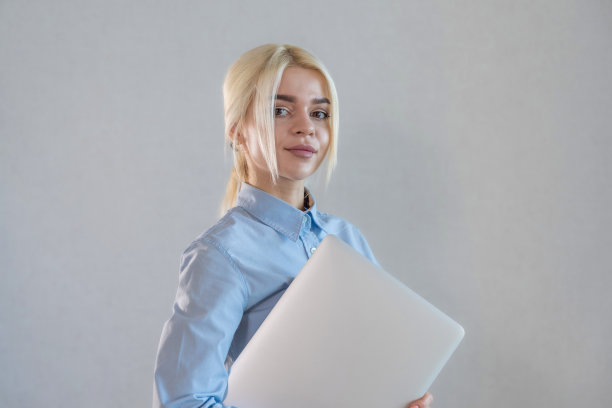 年轻的金发女人站在办公室的笔记本电脑肖像。银行或经理实习女见习生图片下载