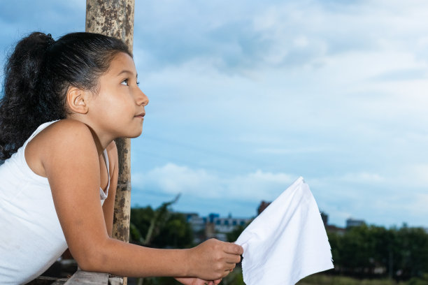一个黑发的拉丁女孩举着白旗仰望天空的照片，自由的概念图片下载