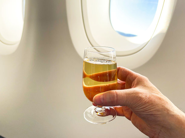 一杯香槟靠在一架客机的窗户上图片下载