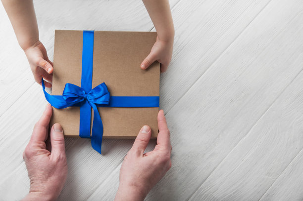 父亲节快乐明信片。孩子给爸爸礼物，爷爷特写。儿童和成人的手图片下载