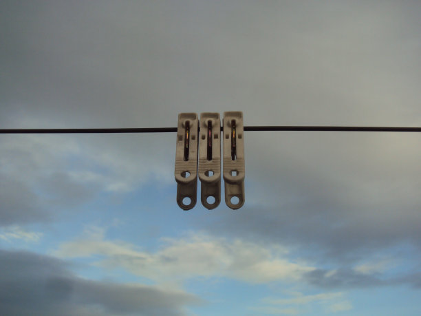 晾衣绳上的晾衣夹，背景是天空图片下载