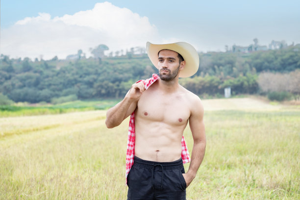 英俊的年轻人，一个完美的身体摆着牛仔帽图片下载