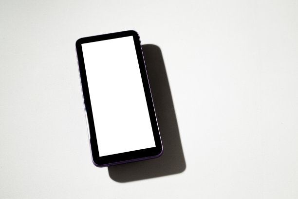 灰色桌子上有白色屏幕的智能手机。图片下载