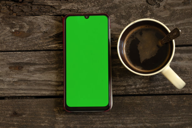一个绿色屏幕的电话放在一块旧黑板上，旁边是一个装有咖啡的杯子图片下载