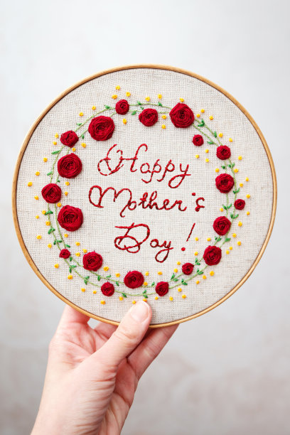 “母亲节快乐”的铭文被绣在织物上的一个花框里。图片下载