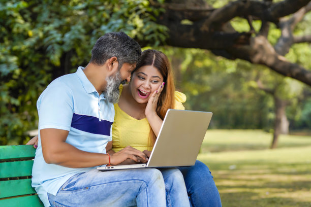 印度男人和女人在公园用笔记本电脑看一些细节。图片下载
