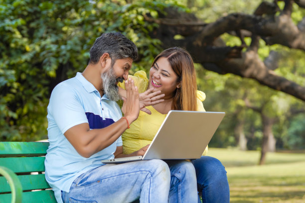 印度男人和女人在公园用笔记本电脑看一些细节。图片下载