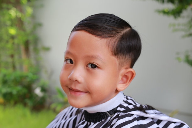 亚洲男孩的肖像剪在花园里，时尚的发型为一个男人。图片下载