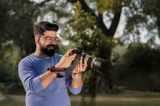 年轻的印度男子在公园使用相机设备图片下载