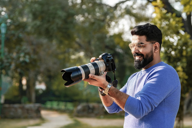 年轻的印度男子在公园使用相机设备图片下载