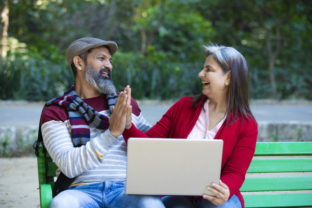 印度老夫妇在公园使用笔记本电脑。图片下载