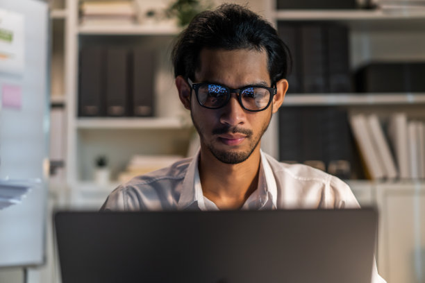 精疲力竭的亚洲年轻商人在办公室的桌子上工作。在公司工作场所的电脑桌上，忙碌的员工们会因为加班和加班而感到疲惫和头痛图片下载