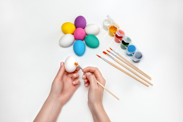 准备复活节。妈妈在蓝色的背景上画复活节彩蛋。复活节图片下载