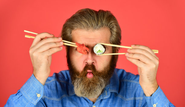 美味的寿司卷。日本传统健康食品。日本寿司。男子用筷子吃传统的日本食物。在家吃晚饭。潮人用筷子吃寿司图片下载