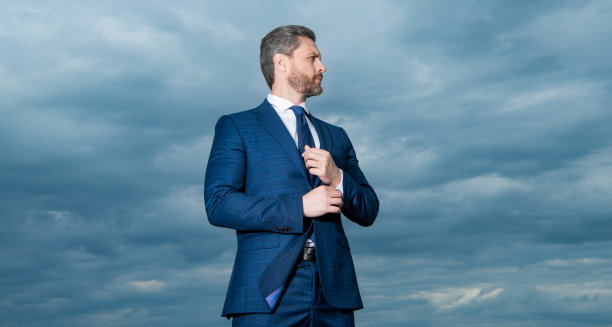 在户外西装男子的照片。在天空背景的西装男子。在户外穿西装的男人。图片下载