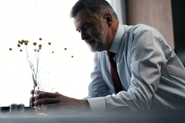 自信，富有，成熟，富有的商人，下班后在厨房放松，喝酒，享受威士忌。图片下载