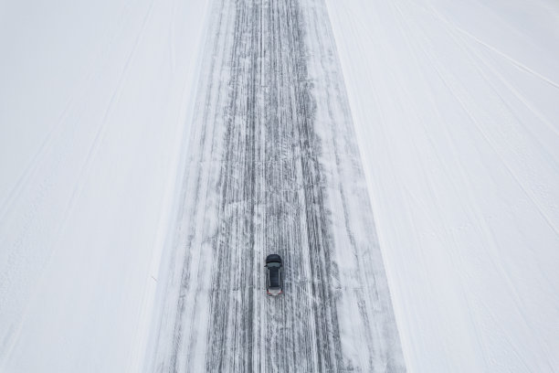 俯视一辆行驶在空旷结冰道路上的汽车图片下载