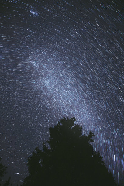 在夜空背景上不寻常的惊人的星迹。星星的旋转明亮的夜晚星空。大曝光。流星划过深蓝色的天空。想象，幻想，幻觉，梦境图片下载