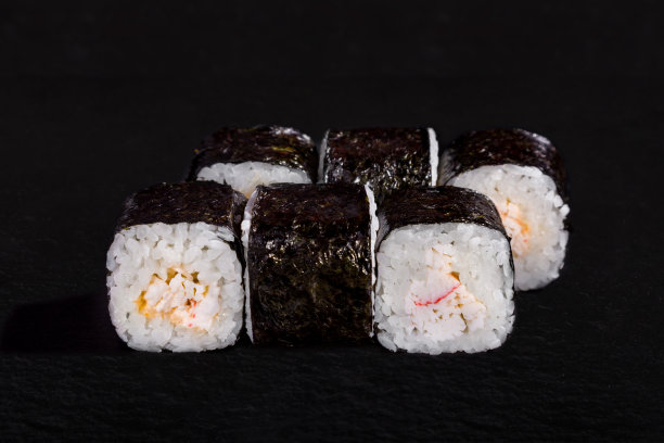 以海苔、米饭、蟹肉和酱汁为背景的黑色石头卷图片下载