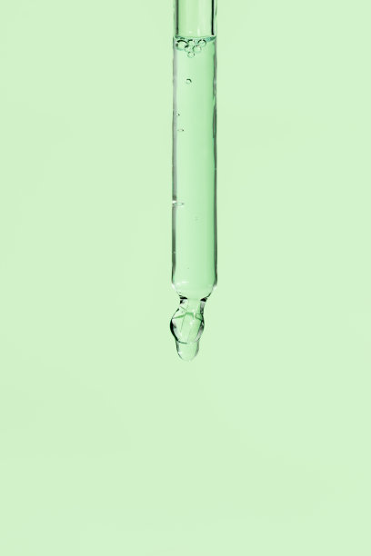 玻璃移液管，浅绿色背景上的面部精华液。带有气泡的液体护肤化妆品特写。精油滴宏。滴管抗衰老皮肤治疗图片下载