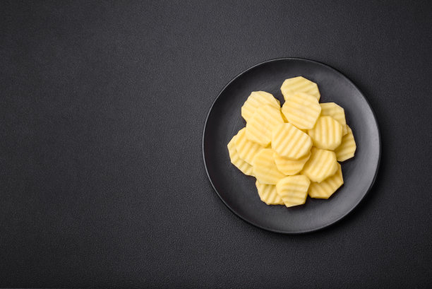 新鲜的土豆切成片放在黑色的陶瓷盘子上图片下载