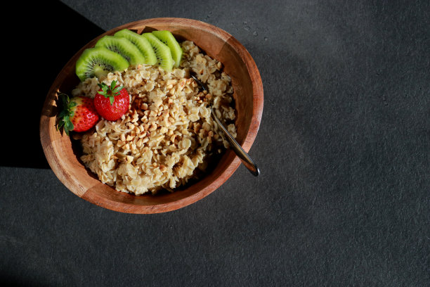 俯视图健康自制燕麦片在一个木碗和水果在灰色大理石桌子图片下载