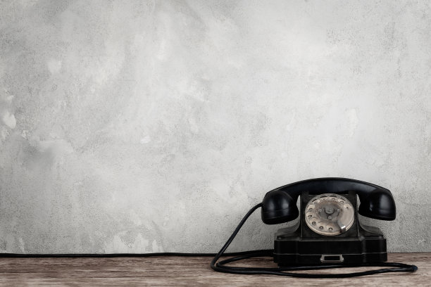 复古的黑色旋转电话在木制桌子前面灰色混凝土背景图片下载