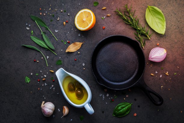 空旧铸铁炉料在黑色的石头背景。制作牛排概念的材料复制空间。各种草药和调味料迷迭香，鼠尾草，月桂叶，罗勒，大蒜和胡椒。图片下载