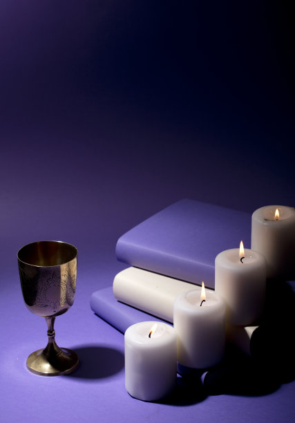 金色的基督圣餐杯，有蜡烛和紫色的背景图片下载