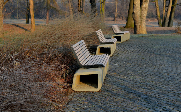 公园长椅两侧有一个扁平的混凝土管底座。这个长凳是用混凝土在3d打印机上打印出来的。水泥块被挤压成螺旋状。上面有一个木制座椅和靠背图片下载