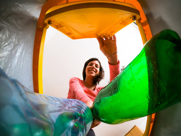 一位年轻女子将塑料瓶放入回收箱图片下载