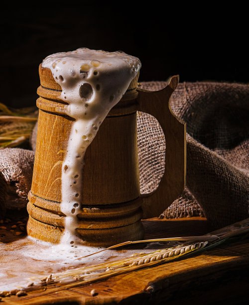 木桌上放着啤酒和泡沫的木制啤酒杯图片下载