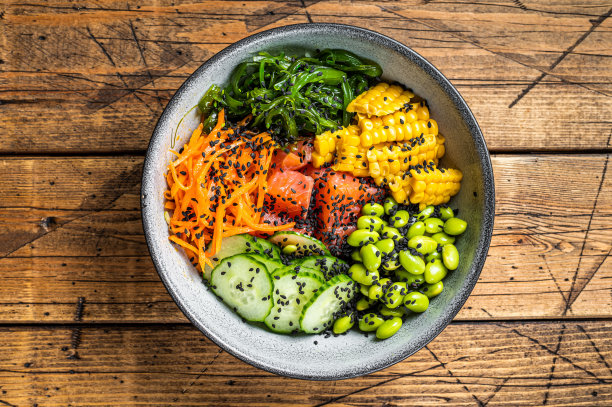 用新鲜三文鱼，米饭，海带，毛豆，黄瓜和黑芝麻戳碗。木制背景。俯视图图片下载