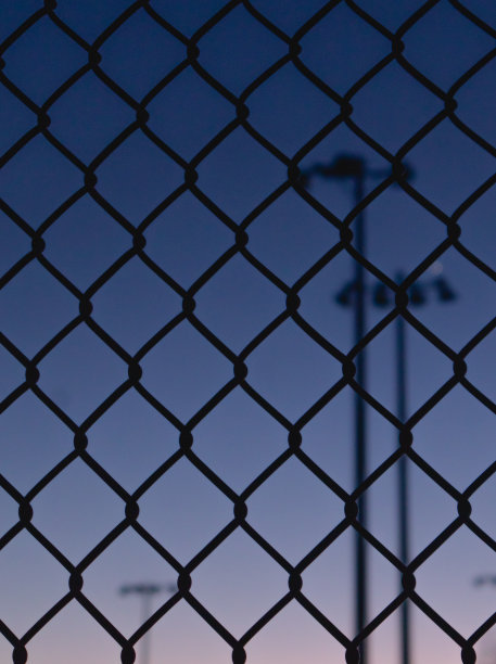 黄昏时网球场栅栏的特写图片下载