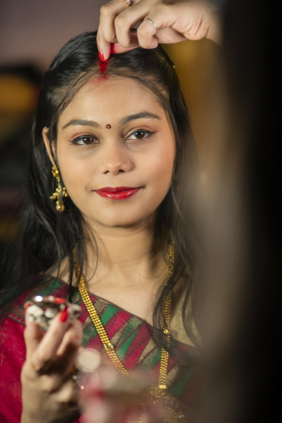 穿着纱丽的美丽已婚印度女子，在镜子前应用Sindoor。图片下载