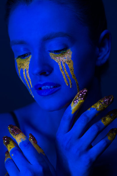 时尚的肖像。一个身上涂着荧光颜料的女孩在霓虹灯下摆姿势。图片下载