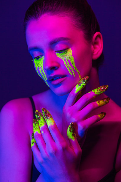 时尚的肖像。一个身上涂着荧光颜料的女孩在霓虹灯下摆姿势。图片下载