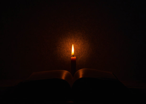在温暖的房间里，点燃的蜡烛在打开的书里燃烧图片下载