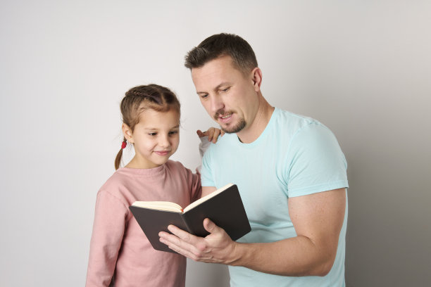 年轻的父亲和女儿阅读书籍特写。图片下载