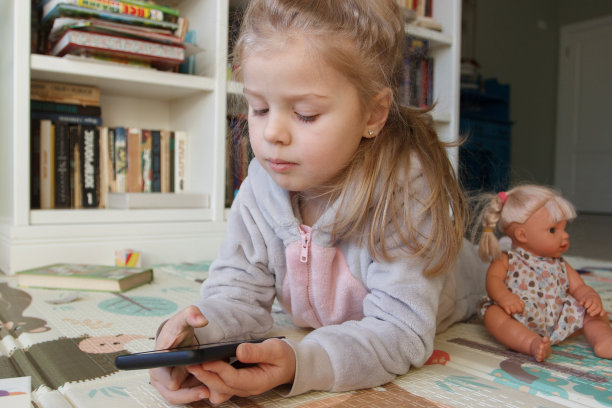 可爱的小孩拿着绿色屏幕的智能手机。在线教育的概念图片下载