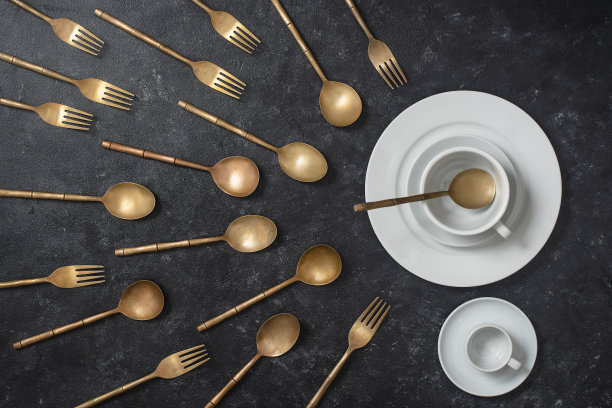 白色的陶瓷盘子，杯子和黄铜叉子和勺子看起来像精子比赛。精子浮在胚珠上图片下载