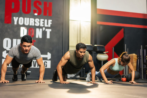 一群年轻的男女运动员一起健身。帅气帅气的男女运动员在健身馆里通过俯卧撑来保持强壮的肌肉，达到保健的目的。图片下载