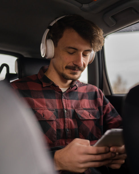 男士带着耳机在车里用手机听音乐或播客图片下载