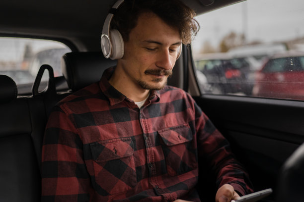 男士带着耳机在车里用手机听音乐或播客图片下载