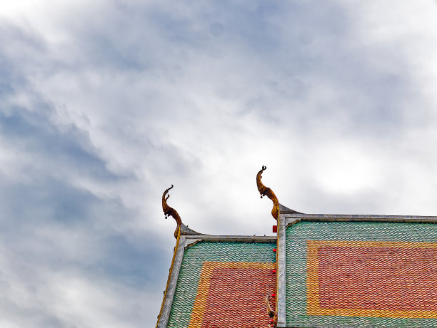 多云天空下的泰国佛教寺庙屋顶的低角度视图图片下载
