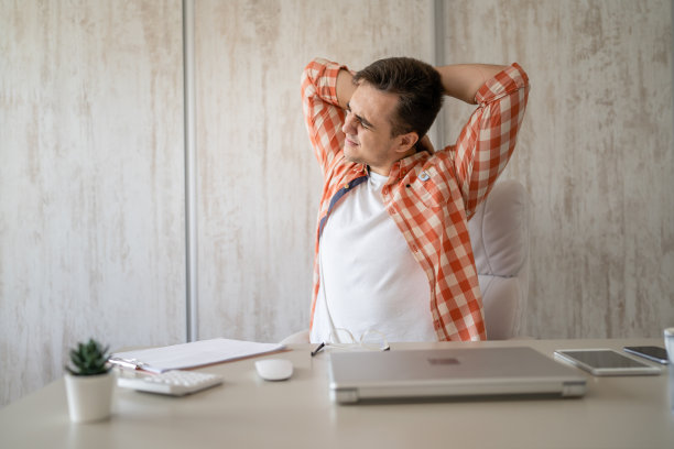 年轻男子在工作时坐在办公桌前伸展腰痛图片下载